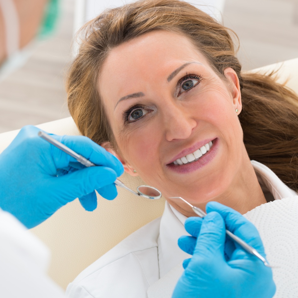 Happy Mature Woman Having Dental Check-up In Clinic