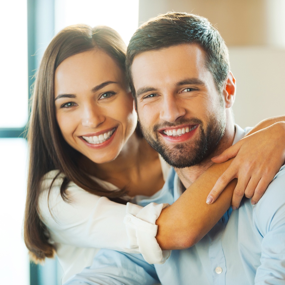 Beautiful young loving couple sitting together on the couch while woman embracing her boyfriend and smiling ** Note: Shallow depth of field