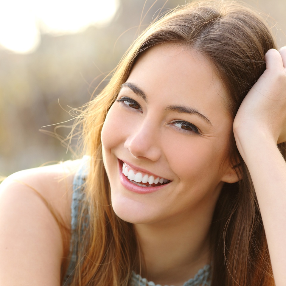 Woman smiling with perfect smile and white teeth in a park and looking at camera