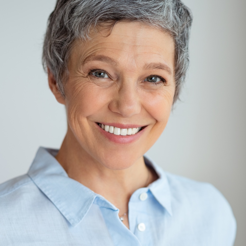 Portrait of happy senior woman isolated against gray background with copy space. Closeup face of confident business woman smiling. Successful businesswoman with a friendly smile looking at camera.