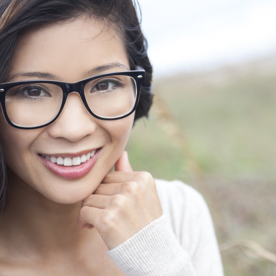 Smiling happy beautiful young Asian Chinese woman or girl wearing geek glasses outside
