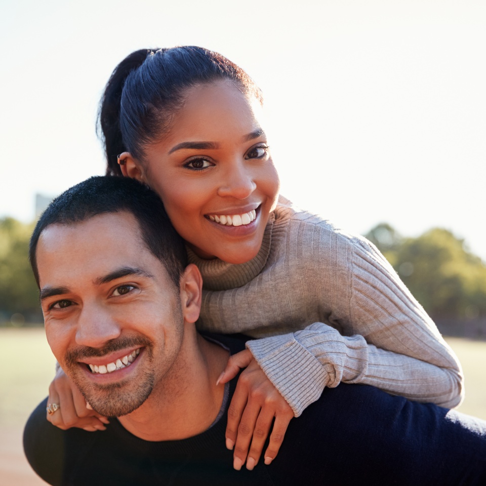 Young couple smiling at camera in Brooklyn, close up